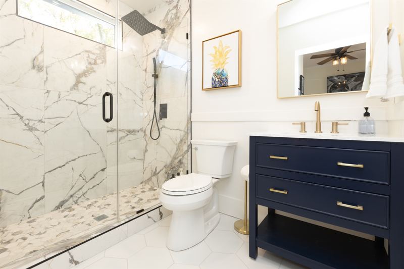 Main House Bottom Unit En-Suite Bathroom #1 with floor to ceiling porcelain tile, walk-in shower with oversized rainfall shower head and handheld shower feature, large in-shower window and vanity,