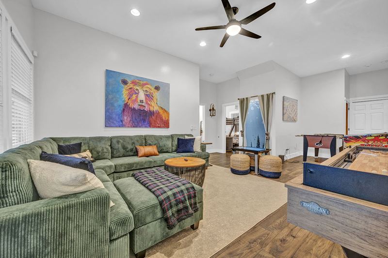 Downstairs game room with cozy large sofa, infinity game, fooseball and suffleboard tables, pinball machine and a cozy nook for the little ones.