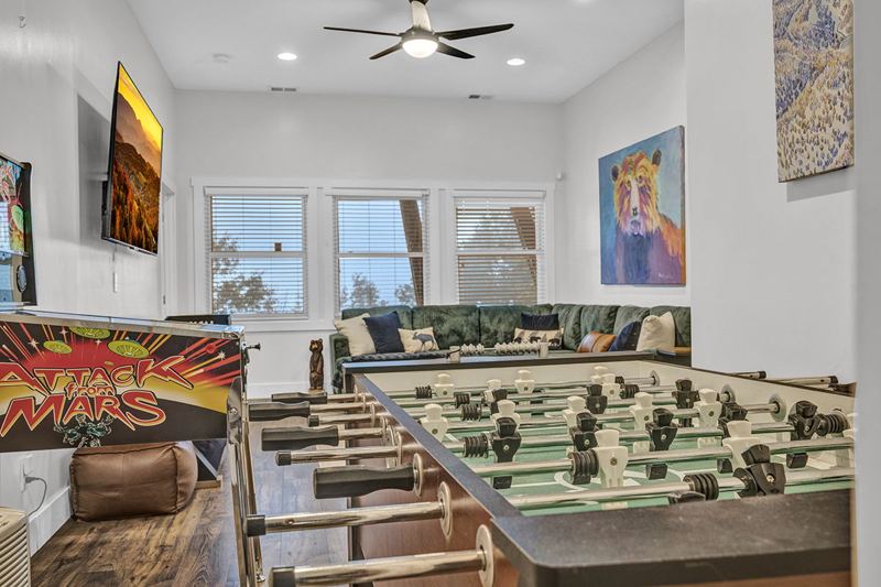 Downstairs game room with cozy large sofa, infinity game, fooseball and suffleboard tables, pinball machine and a cozy nook for the little ones.