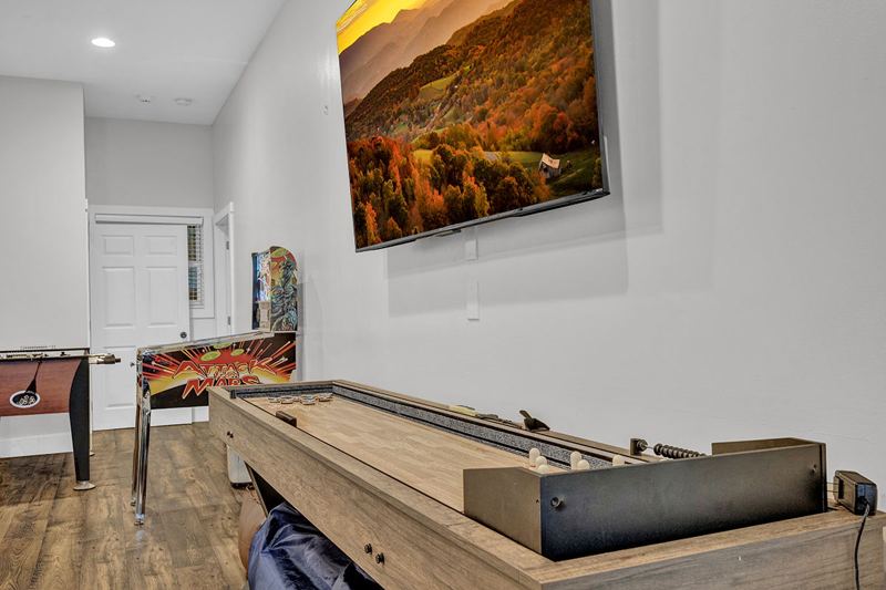 Downstairs game room with cozy large sofa, infinity game, fooseball and suffleboard tables, pinball machine and a cozy nook for the little ones.