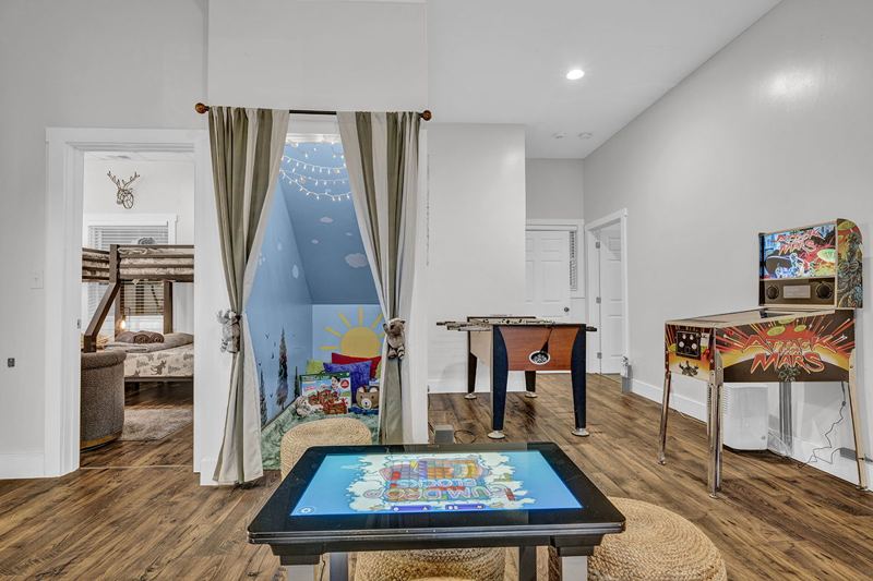 Downstairs game room with cozy large sofa, infinity game, fooseball and suffleboard tables, pinball machine and a cozy nook for the little ones.