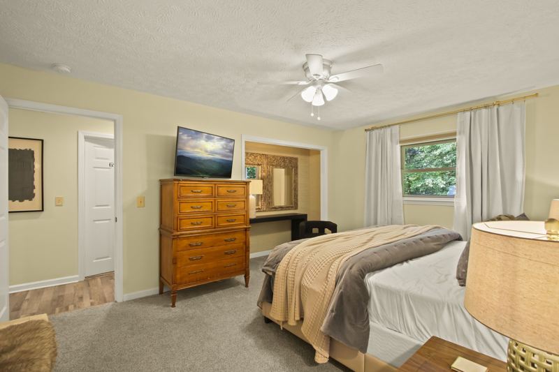 Main Level Bedroom (Spring Room) with King Bed, En-suite full bathroom with dual vanity, 43-inch Smart TV, workstation, large dresser, blackout curtains, white noise machine and luggage rack.