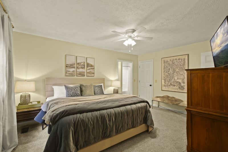 Main Level Bedroom (Spring Room) with King Bed, En-suite full bathroom with dual vanity, 43-inch Smart TV, workstation, large dresser, blackout curtains, white noise machine and luggage rack.
