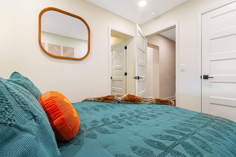 Lower-Level Bedroom with Queen Bed, En-Suite Full Bathroom with floor to ceiling porcelain tile walk-in shower, oversized rainfall shower head and handheld feature, large in-shower window and