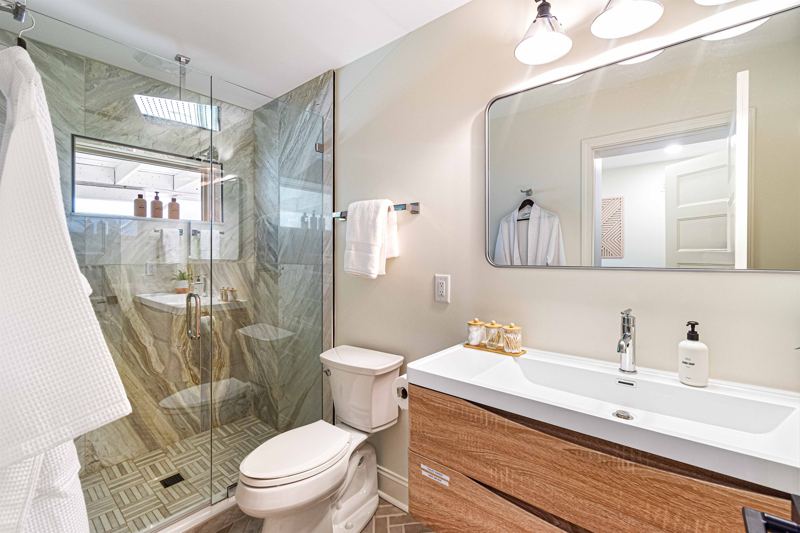 Lower-Level Bedroom En-Suite Full Bathroom with floor to ceiling porcelain tile walk-in shower, oversized rainfall shower head and handheld feature, large in-shower window and double drawer va