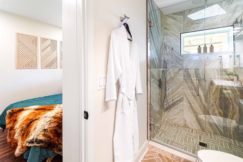 Lower-Level Bedroom En-Suite Full Bathroom with floor to ceiling porcelain tile walk-in shower, oversized rainfall shower head and handheld feature, large in-shower window and double drawer va