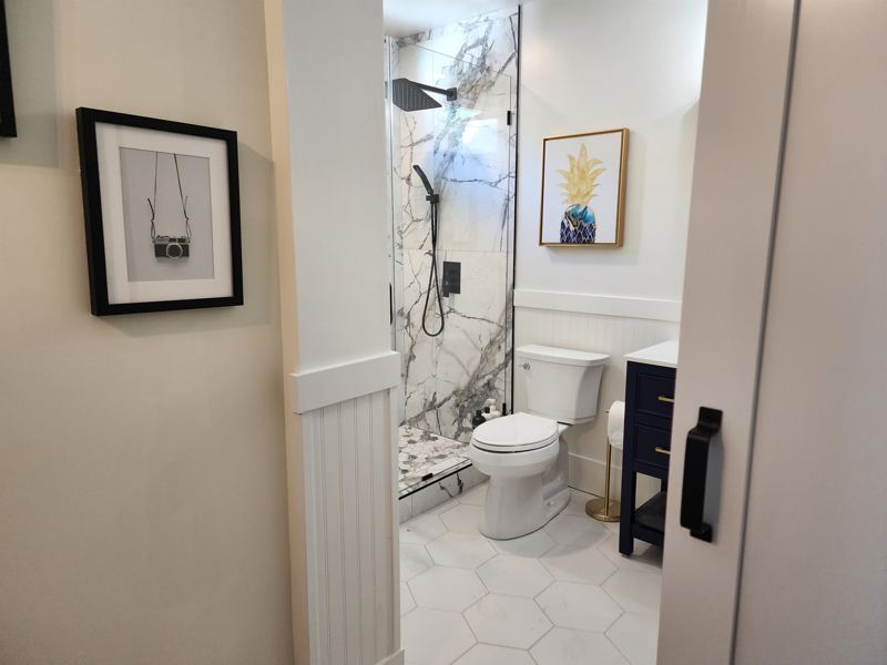 Bathroom #1 with floor to ceiling porcelain tile walk-in shower with an oversized rainfall shower head and handheld shower feature, large in-shower window and vanity.