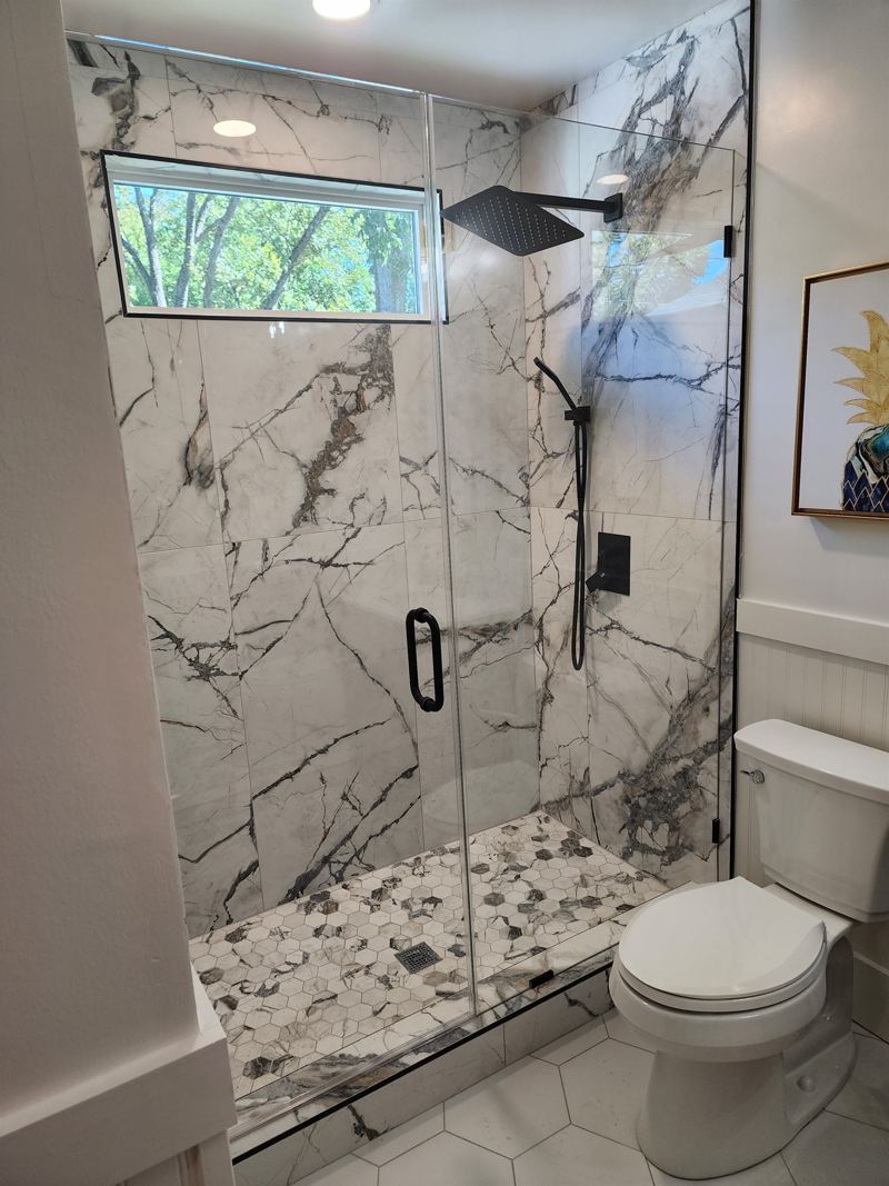 Bathroom #1 with floor to ceiling porcelain tile walk-in shower with an oversized rainfall shower head and handheld shower feature, large in-shower window and vanity.