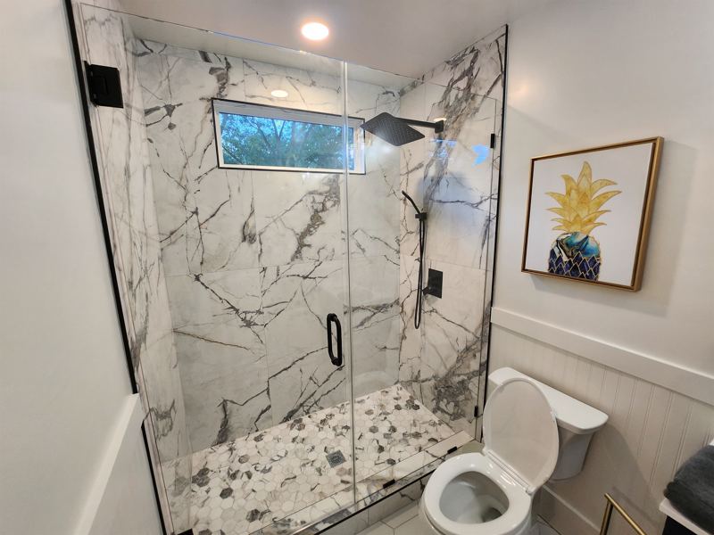 Bottom Floor Unit En-Suite Bathroom #1 with floor to ceiling porcelain tile walk-in shower with oversized rainfall shower head and handheld shower features, large in-shower window and vanity.