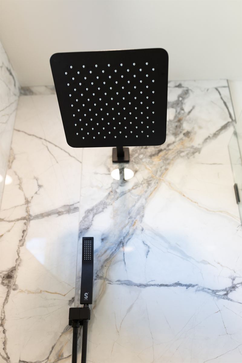 Bottom Floor Unit En-Suite Bathroom #1 with floor to ceiling porcelain tile walk-in shower with oversized rainfall shower head and handheld shower features, large in-shower window and vanity.