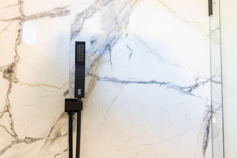 Bottom Floor Unit En-Suite Bathroom #1 with floor to ceiling porcelain tile walk-in shower with oversized rainfall shower head and handheld shower features, large in-shower window and vanity.