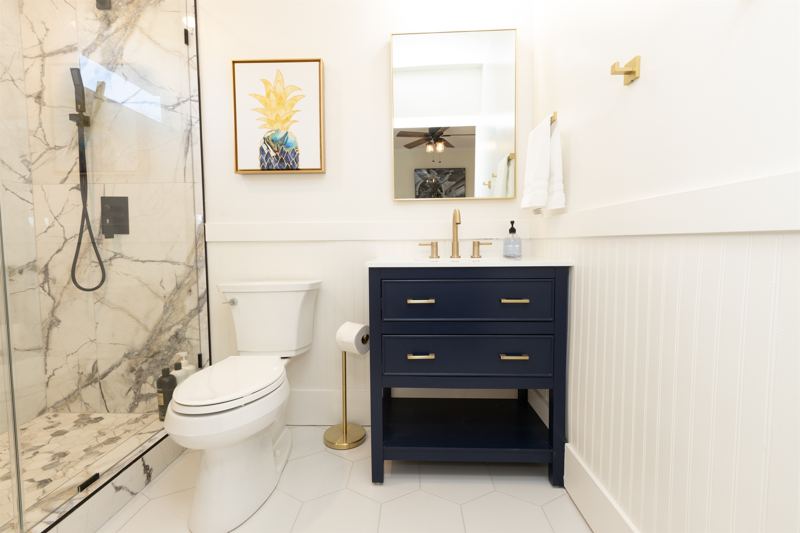 Main House Bottom Unit En-Suite Bathroom #1 with floor to ceiling porcelain tile, walk-in shower with oversized rainfall shower head and hand held shower feature, large in-shower window and vanity.